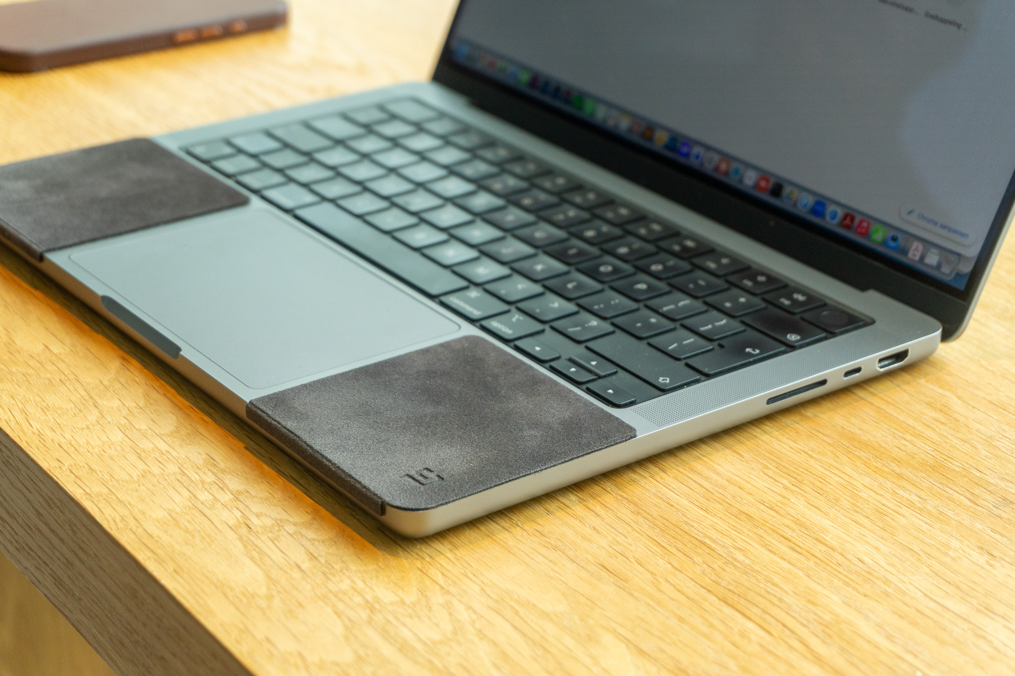 MacBook fitted with ChronoPad palm rest pads on a wooden desk