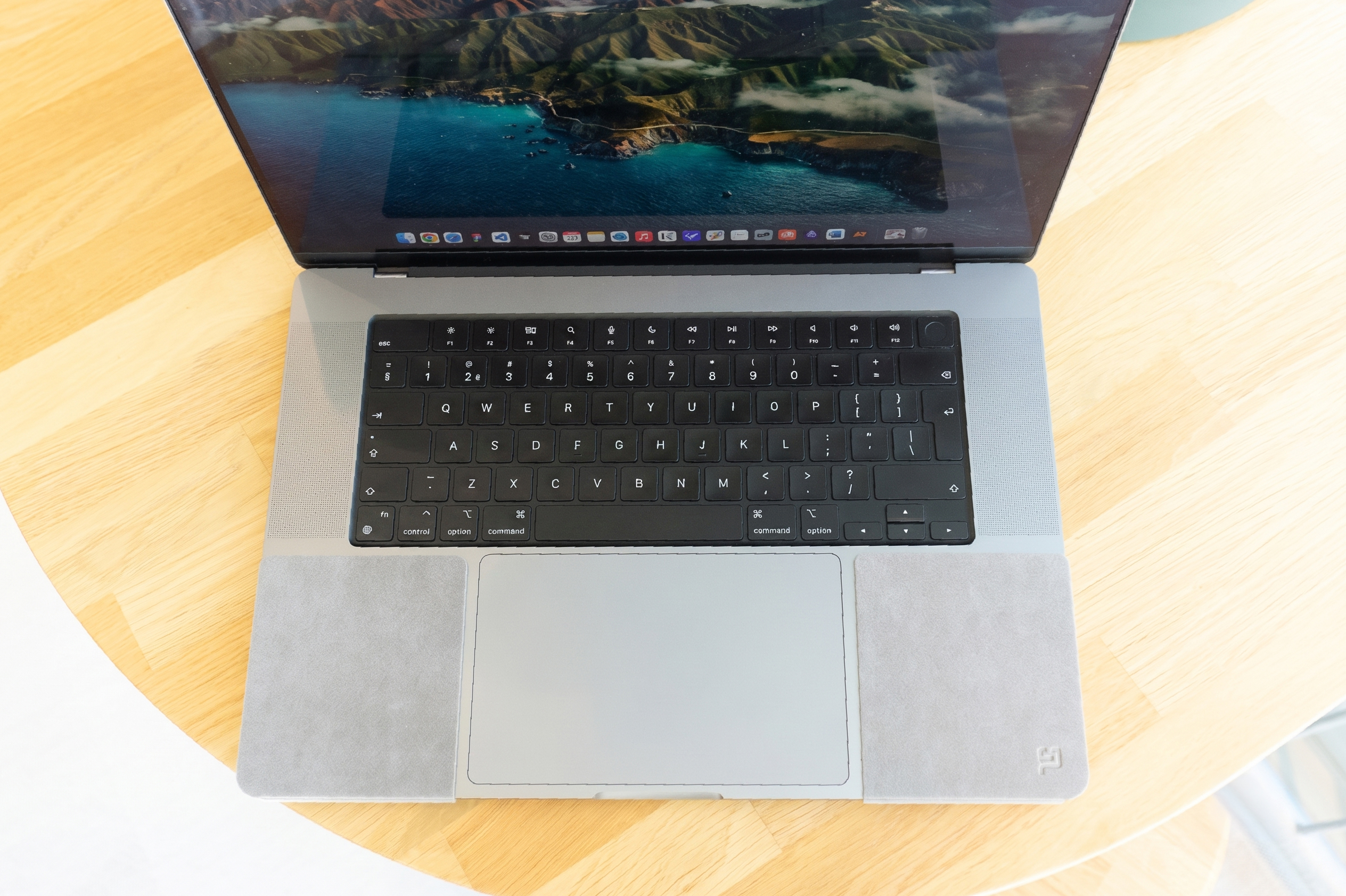 Top-down view of a silver MacBook Pro with two ChronoPad palm rest pads on either side of the trackpad