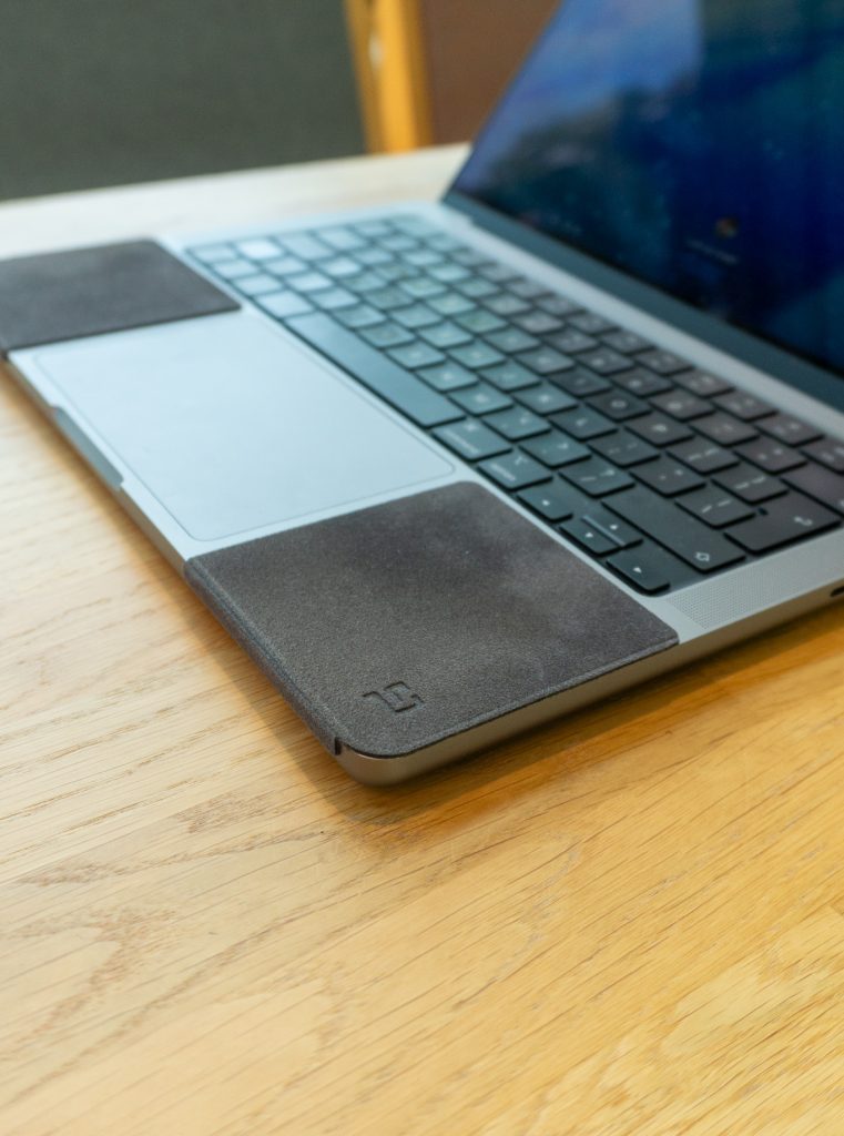 MacBook with ChronoPad pads on both sides of the palm rest, side view