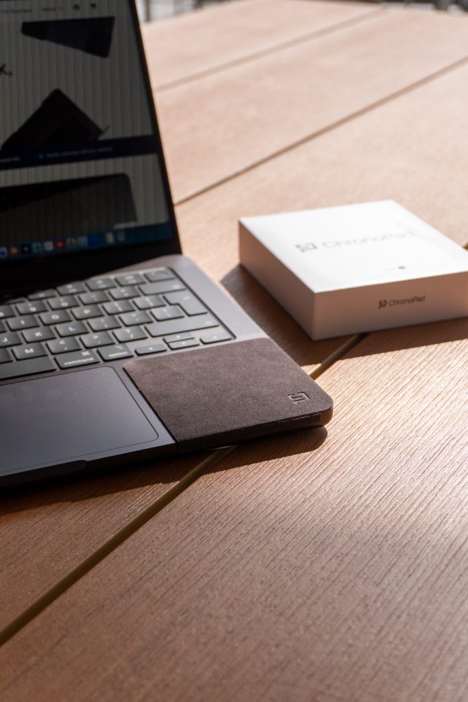 MacBook with ChronoPad applied next to the ChronoPad packaging on a desk