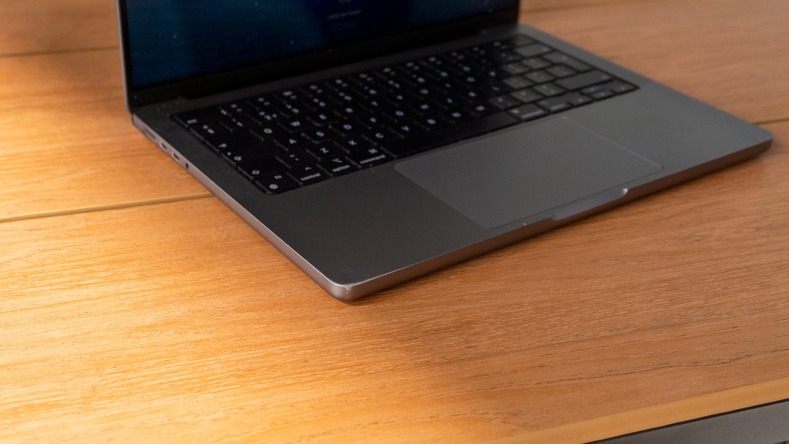 Front edge and palm rest of a MacBook Pro without protection on a wooden desk
